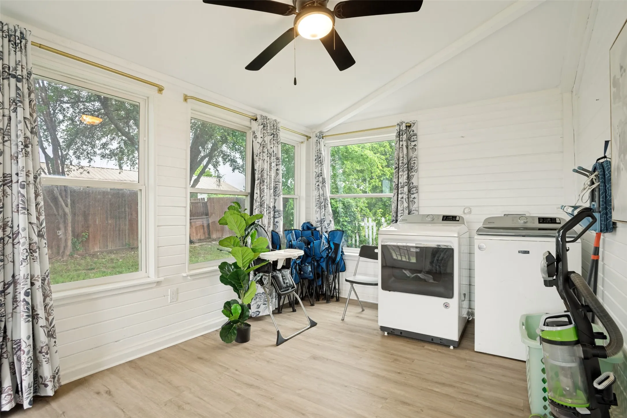 Functional utility space featuring a wood-finish flooring, multiple windows, a ceiling fan, and white shiplap walls