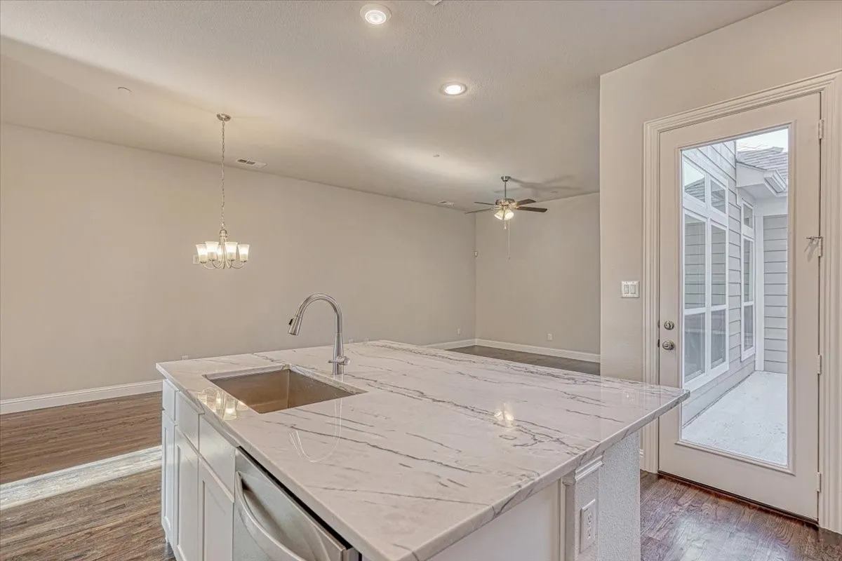 Kitchen with an island with sink, sink, dark hardwood / wood-style floors, and ceiling fan with notable chandelier