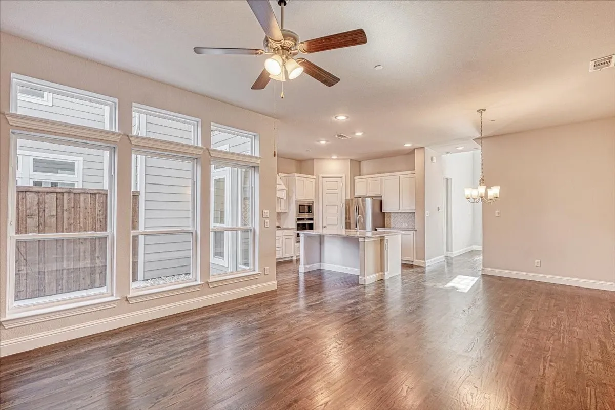 Unfurnished living room featuring dark hardwood / wood-style floors and ceiling fan with notable chandelier