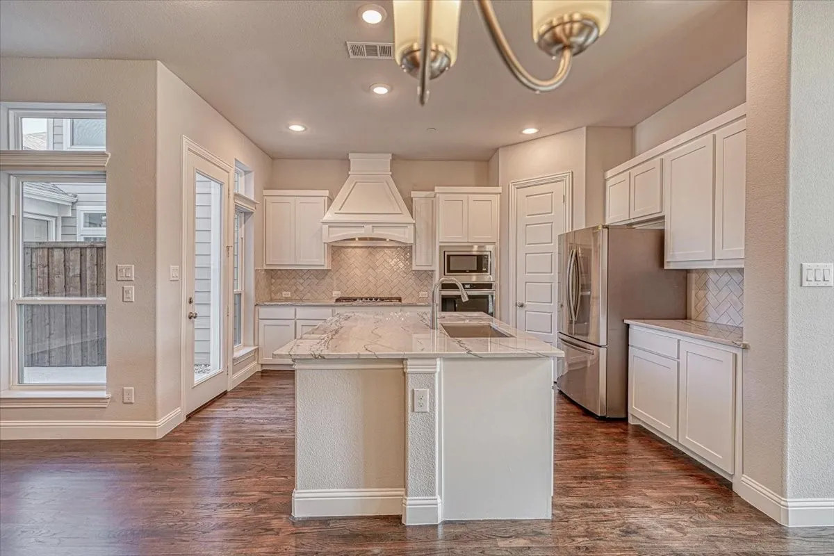 Kitchen with appliances with stainless steel finishes, white cabinetry, premium range hood, and dark hardwood / wood-style floors