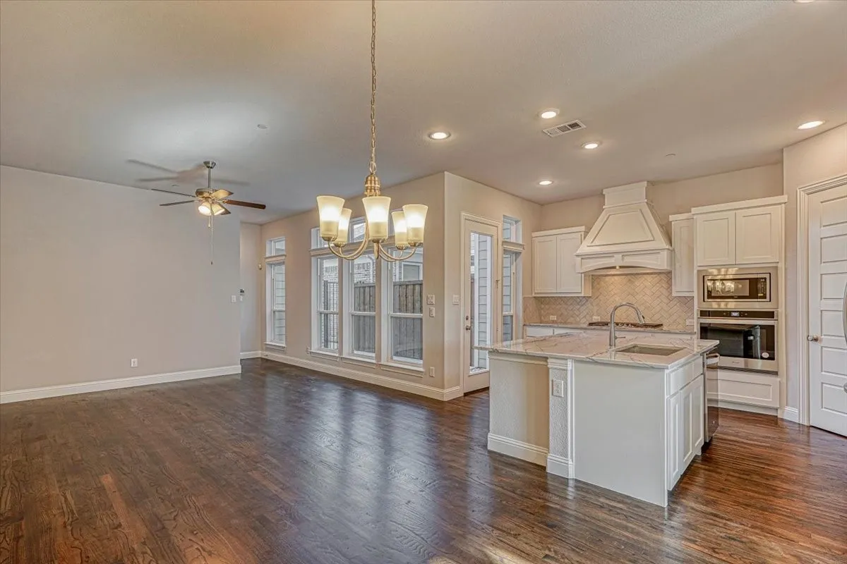 Kitchen featuring stainless steel appliances, custom exhaust hood, an island with sink, and dark hardwood / wood-style floors