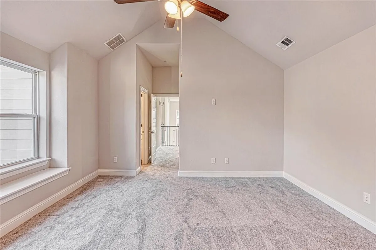 Spare room featuring light carpet, plenty of natural light, ceiling fan, and lofted ceiling