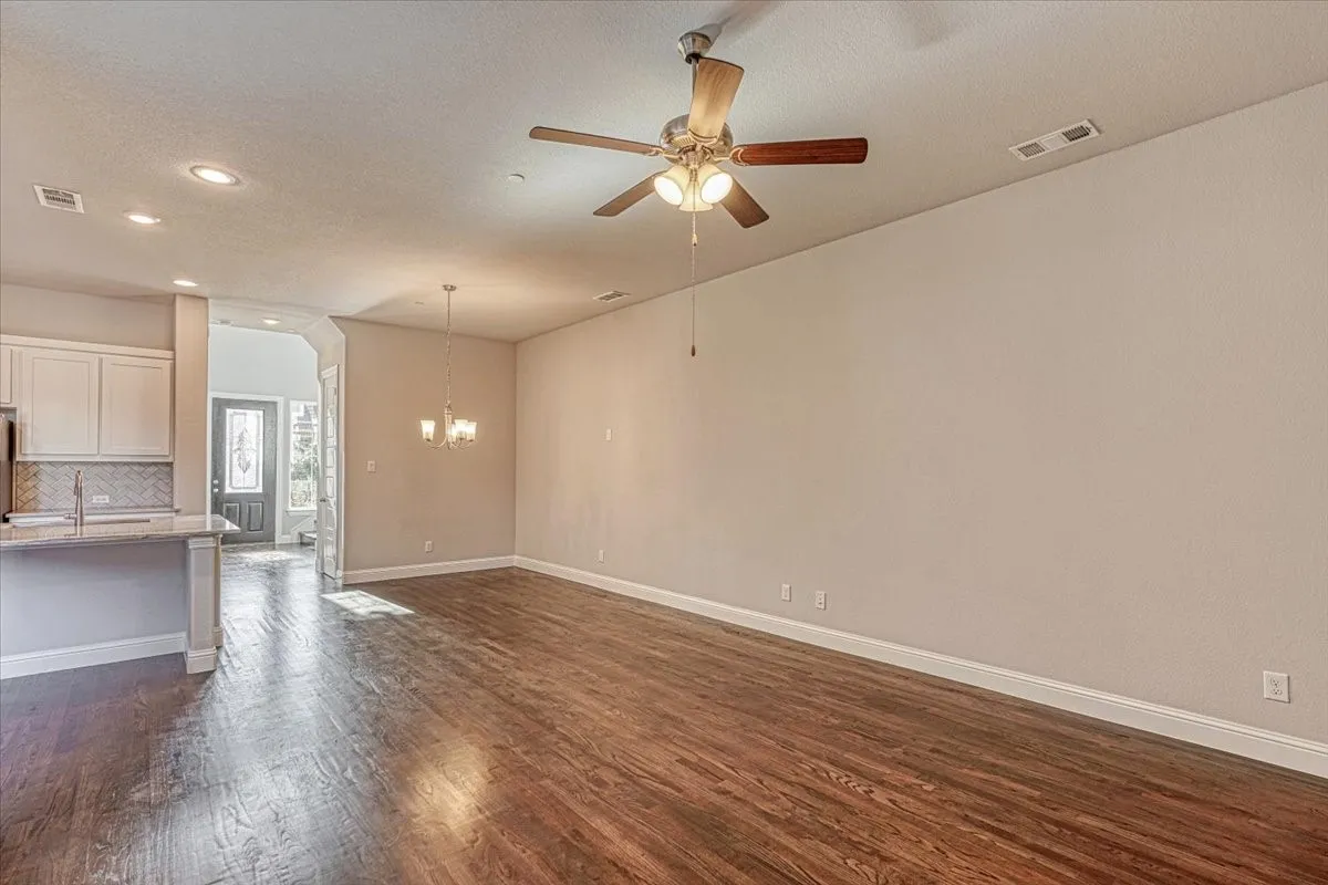 Unfurnished living room featuring ceiling fan with notable chandelier, a textured ceiling, sink, and dark wood-type flooring