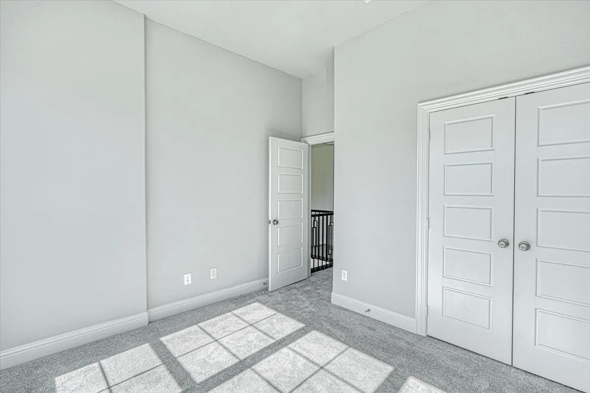 Unfurnished bedroom featuring light carpet and a closet