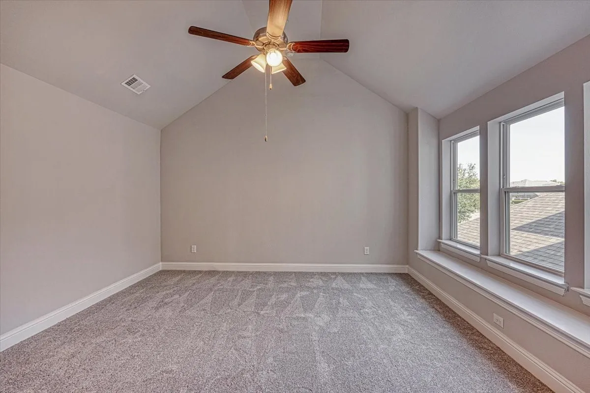 Empty room with carpet, ceiling fan, and lofted ceiling