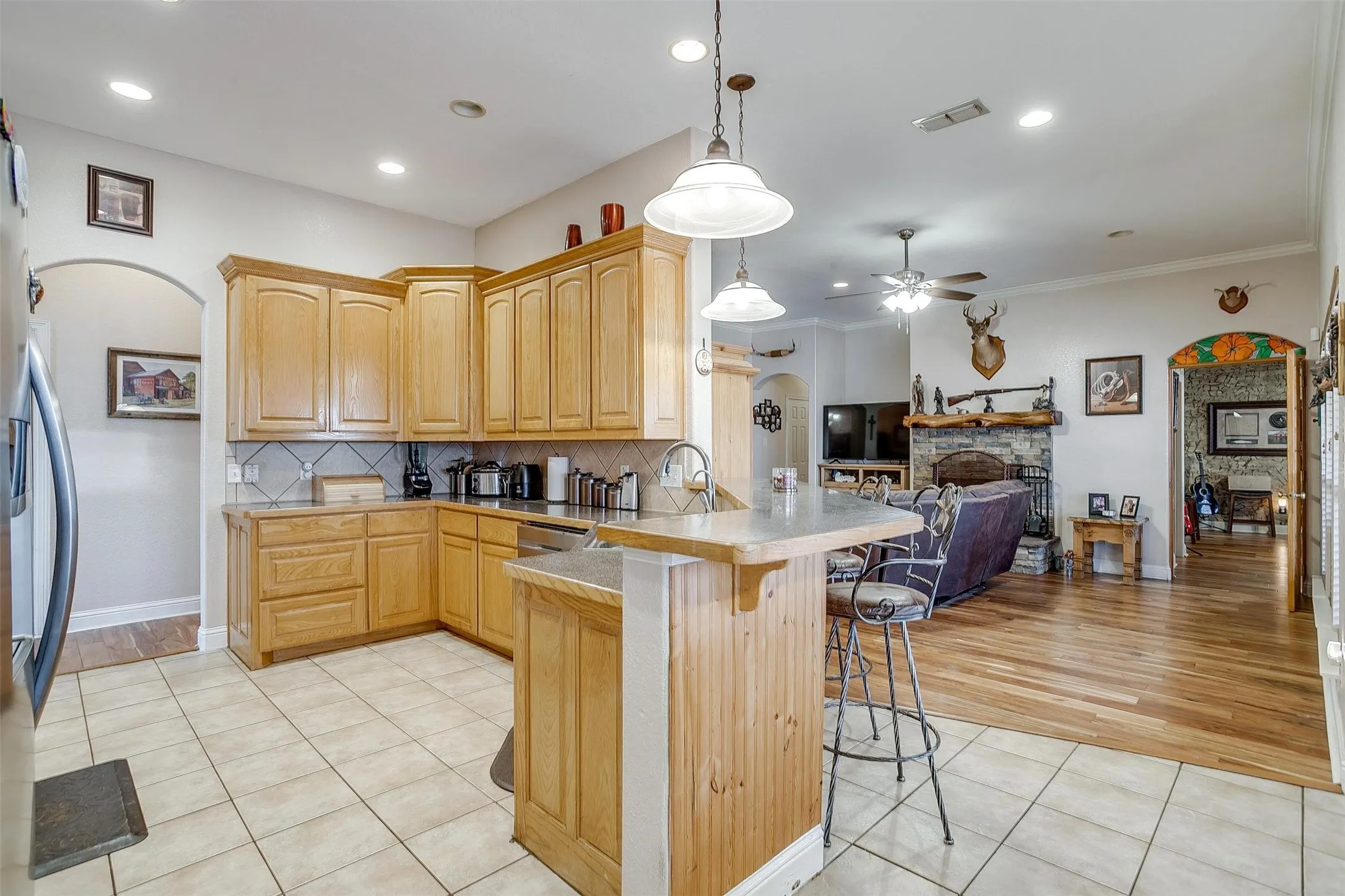 Kitchen featuring a breakfast bar, light brown cabinets, a peninsula, open floor plan, and ceiling fan