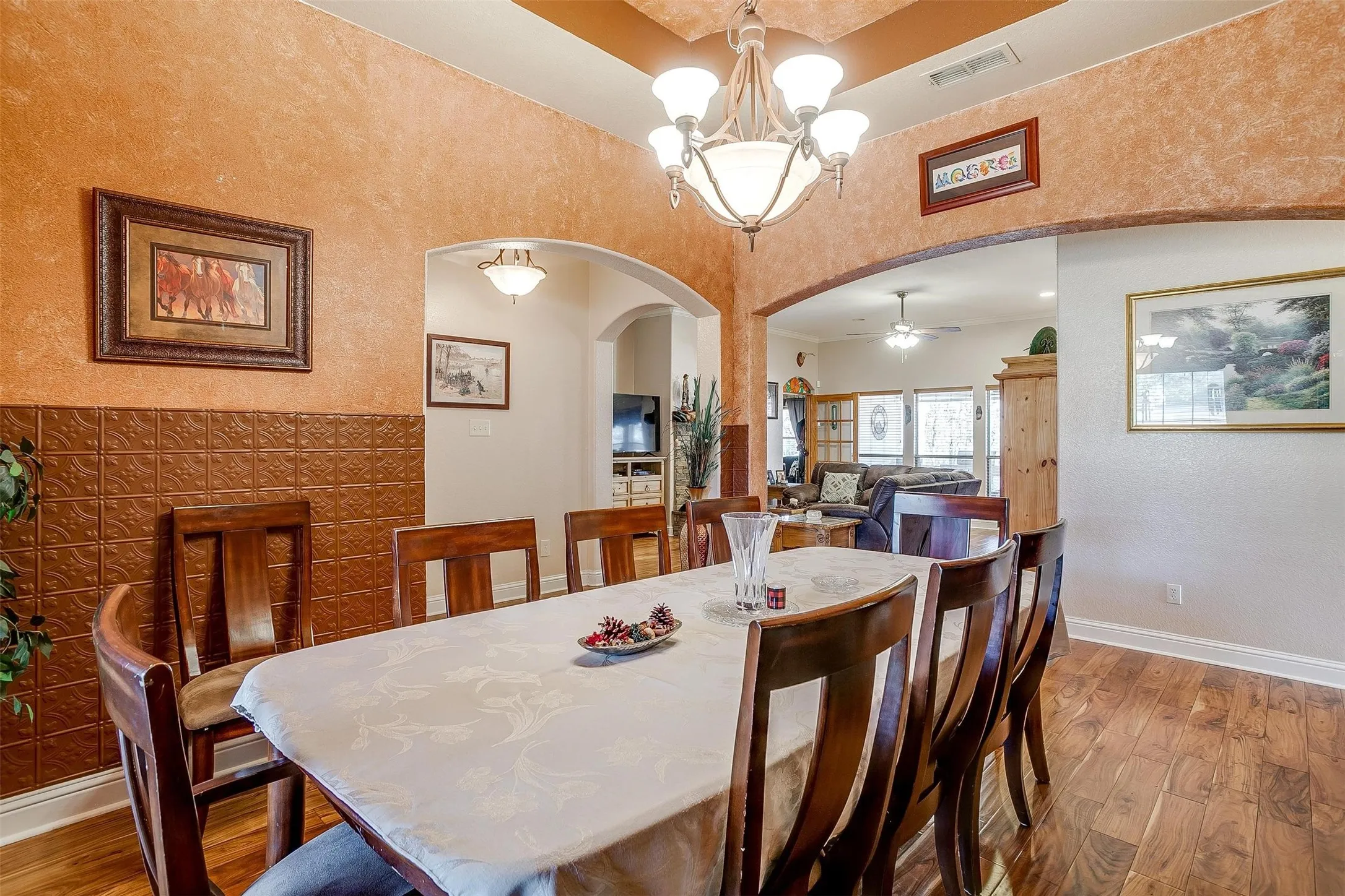 Dining room with arched walkways, visible vents, and hardwood / wood-style flooring