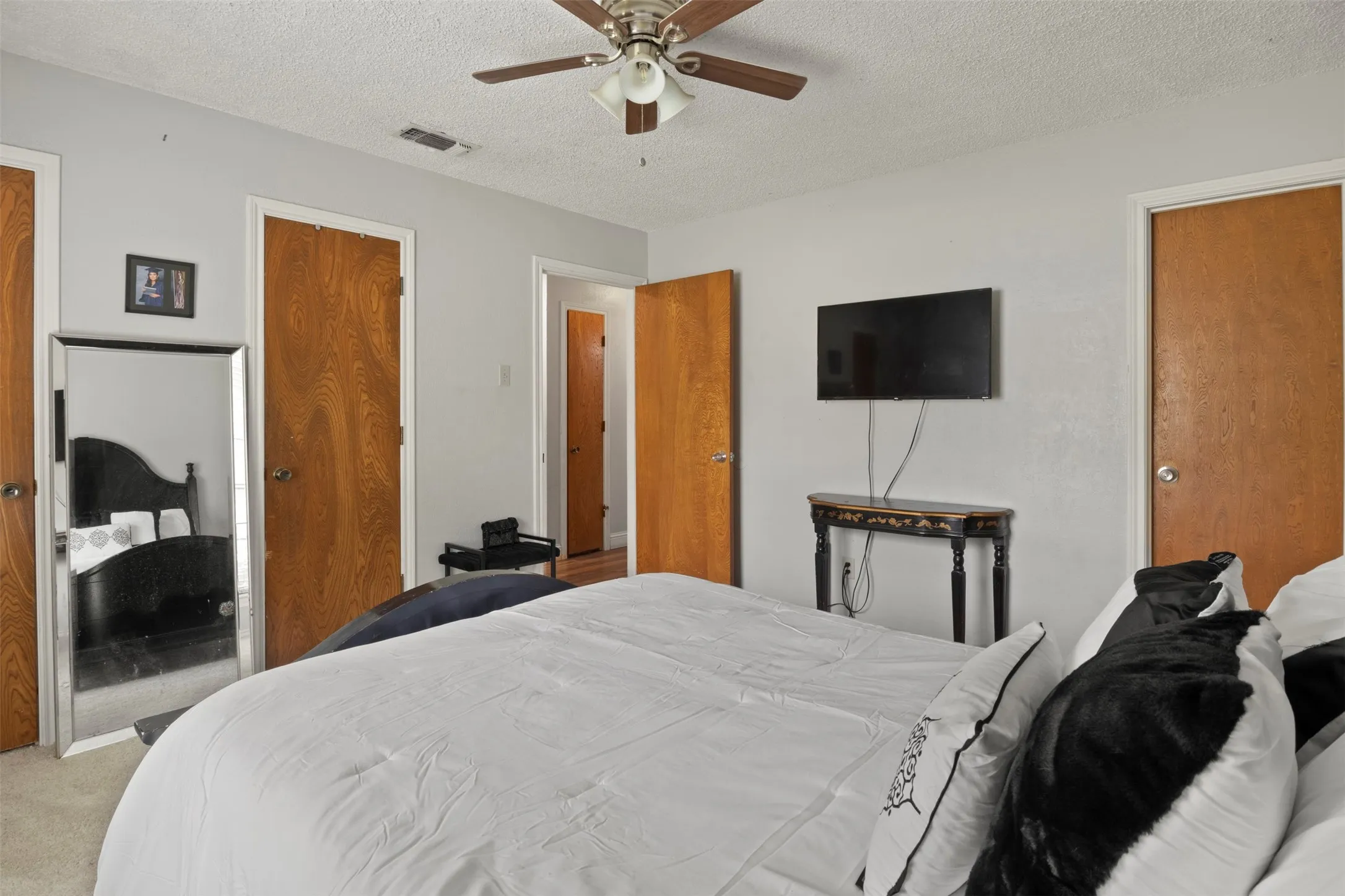 Bedroom featuring light gray walls, wood-finish doors, and a ceiling fan with integrated lighting