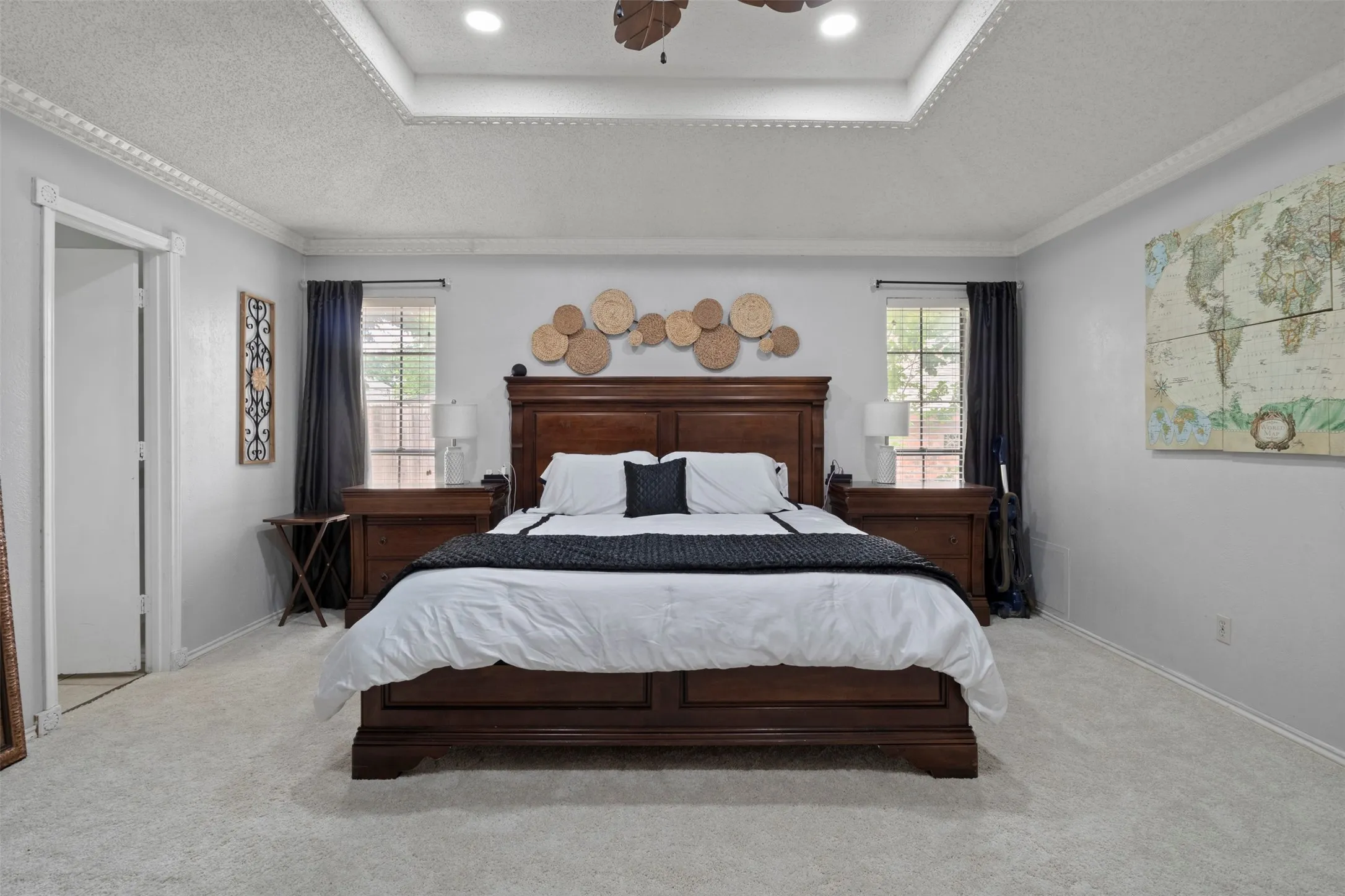 Spacious bedroom featuring plush carpeting, a tray ceiling with recessed lighting, crown molding, and dual windows