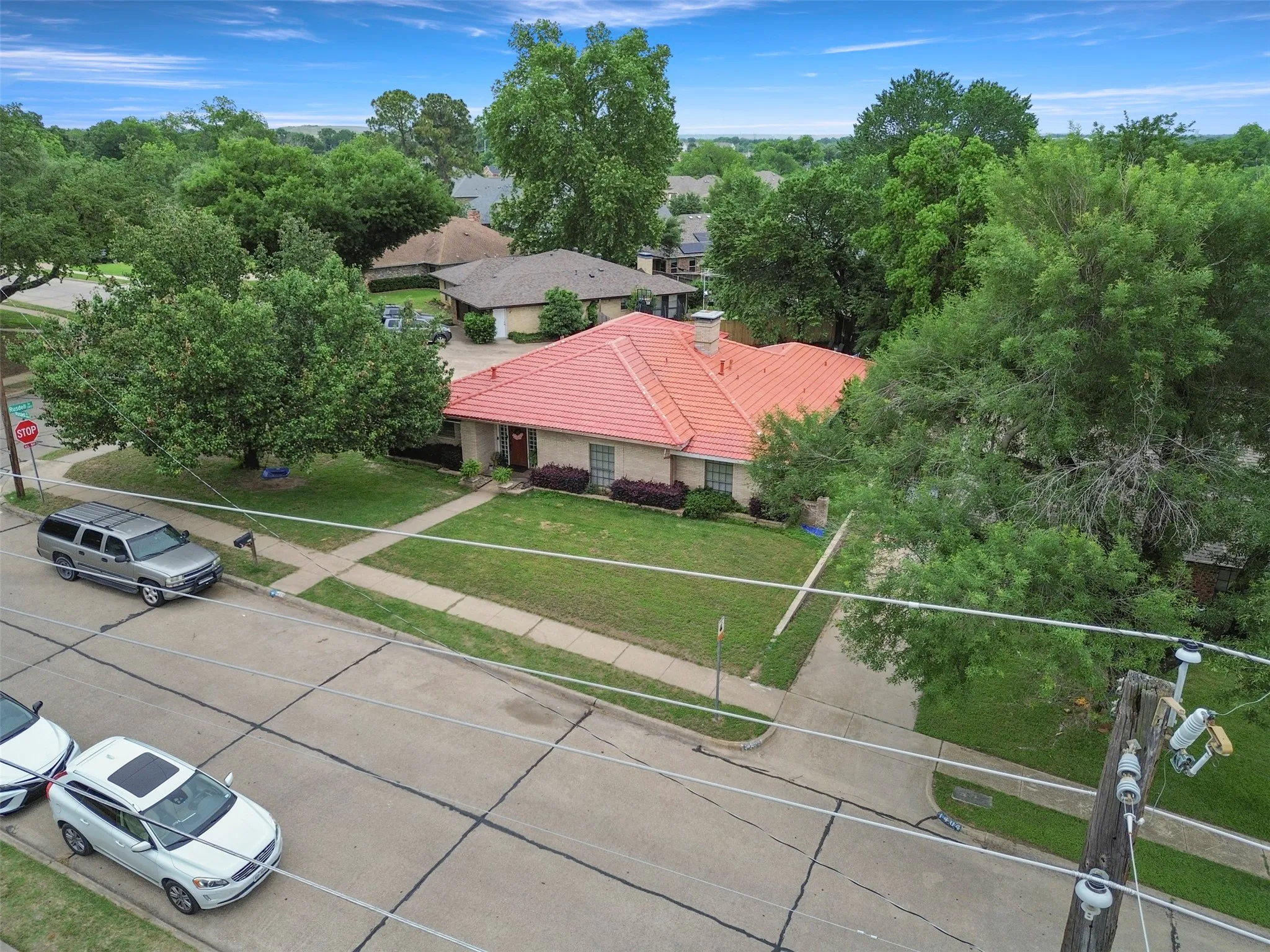 Single-story residence featuring a terracotta-hued tile roof, brick exterior, and an attached front porch