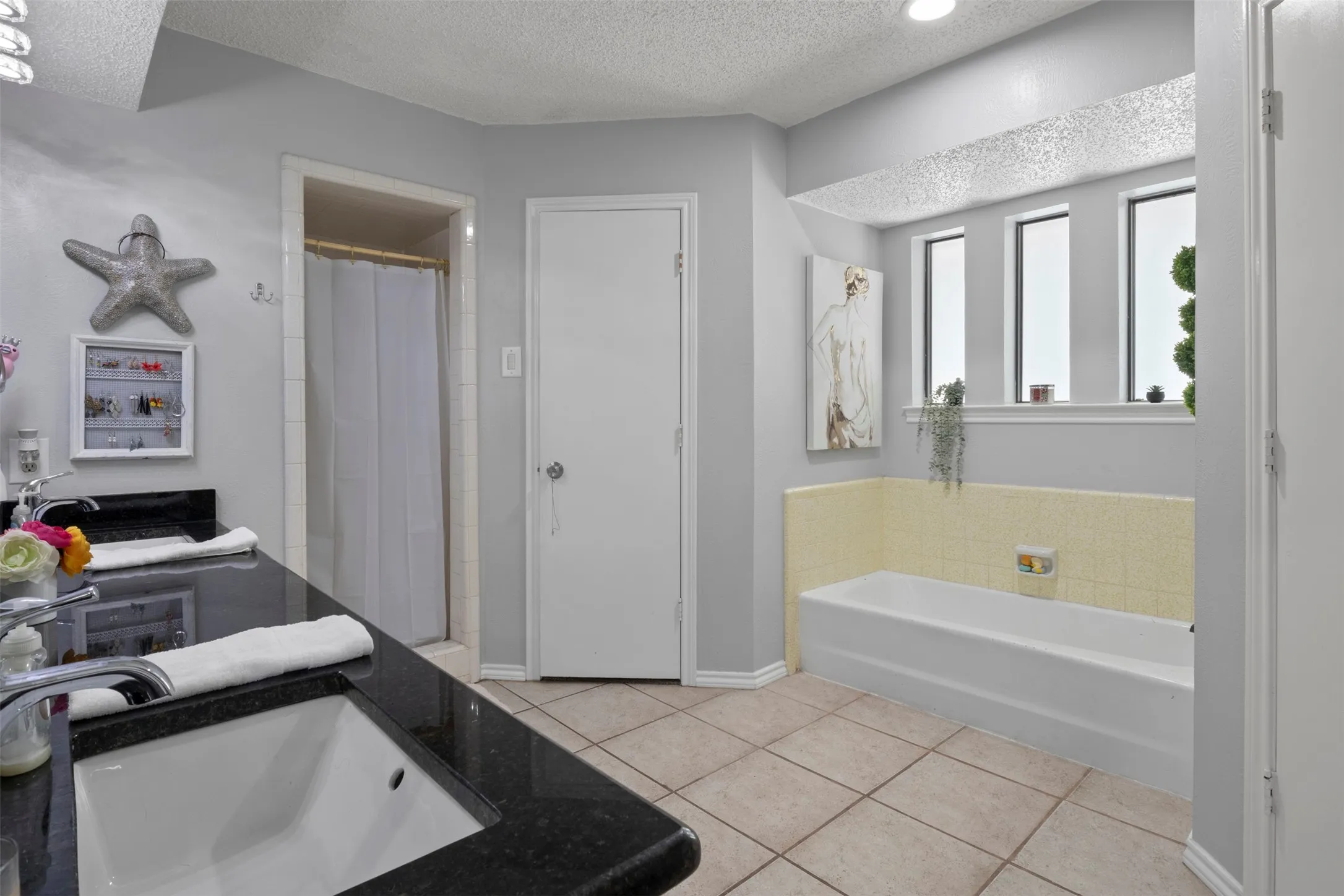 Bathroom featuring a dual-sink vanity with a dark countertop and chrome fixtures