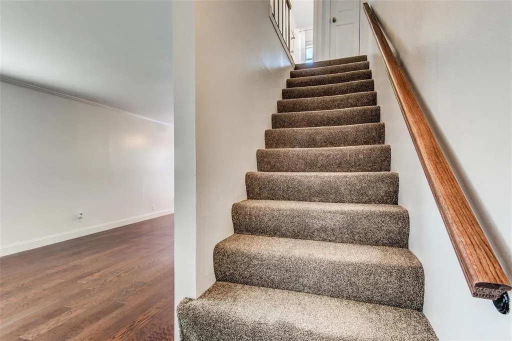 Carpeted staircase with a wood handrail