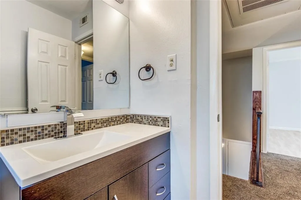 Bathroom vanity featuring an integrated sink, solid surface countertop, and a mosaic tile backsplash