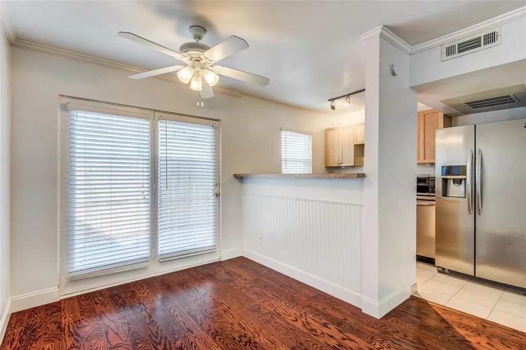 Dining area featuring wood-finish flooring, a ceiling fan with integrated lighting, and crown molding