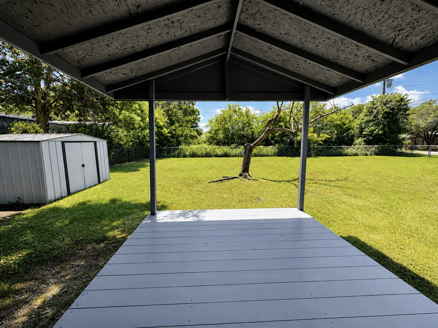 Covered patio with a light gray deck and dark gray support posts