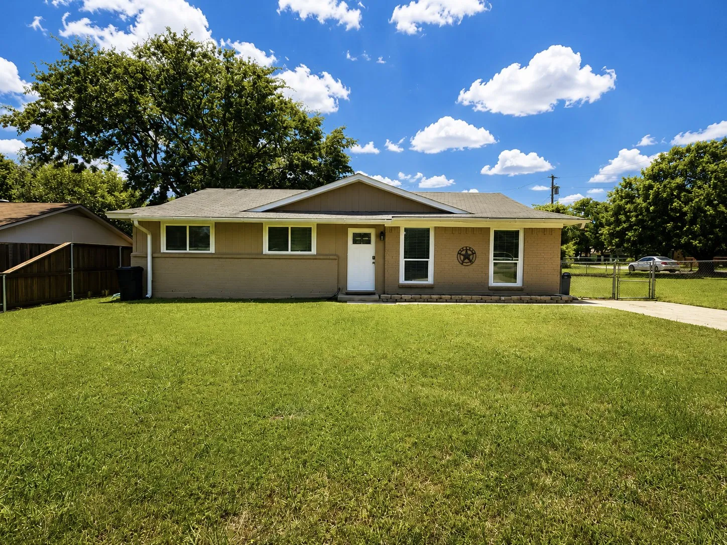 Single-story residence featuring a neutral exterior, white trim windows, and a paved driveway