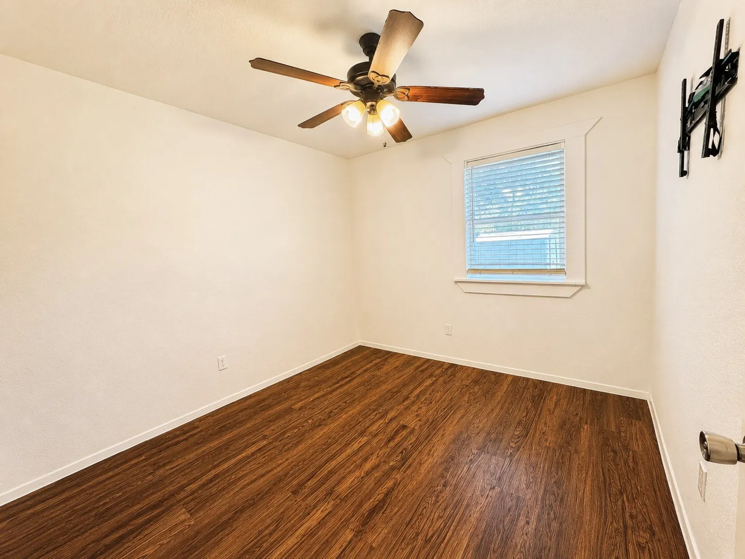 Room featuring wood-finish flooring, a window with horizontal blinds, and a ceiling fan with integrated lighting