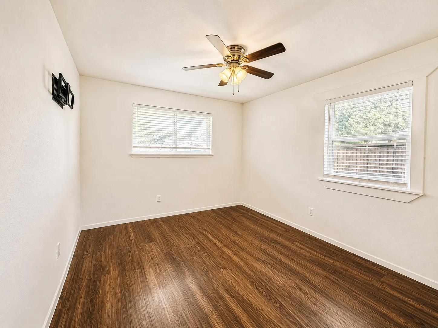 Bright interior space featuring wood-finish flooring, light-toned walls, and a ceiling fan with integrated lighting