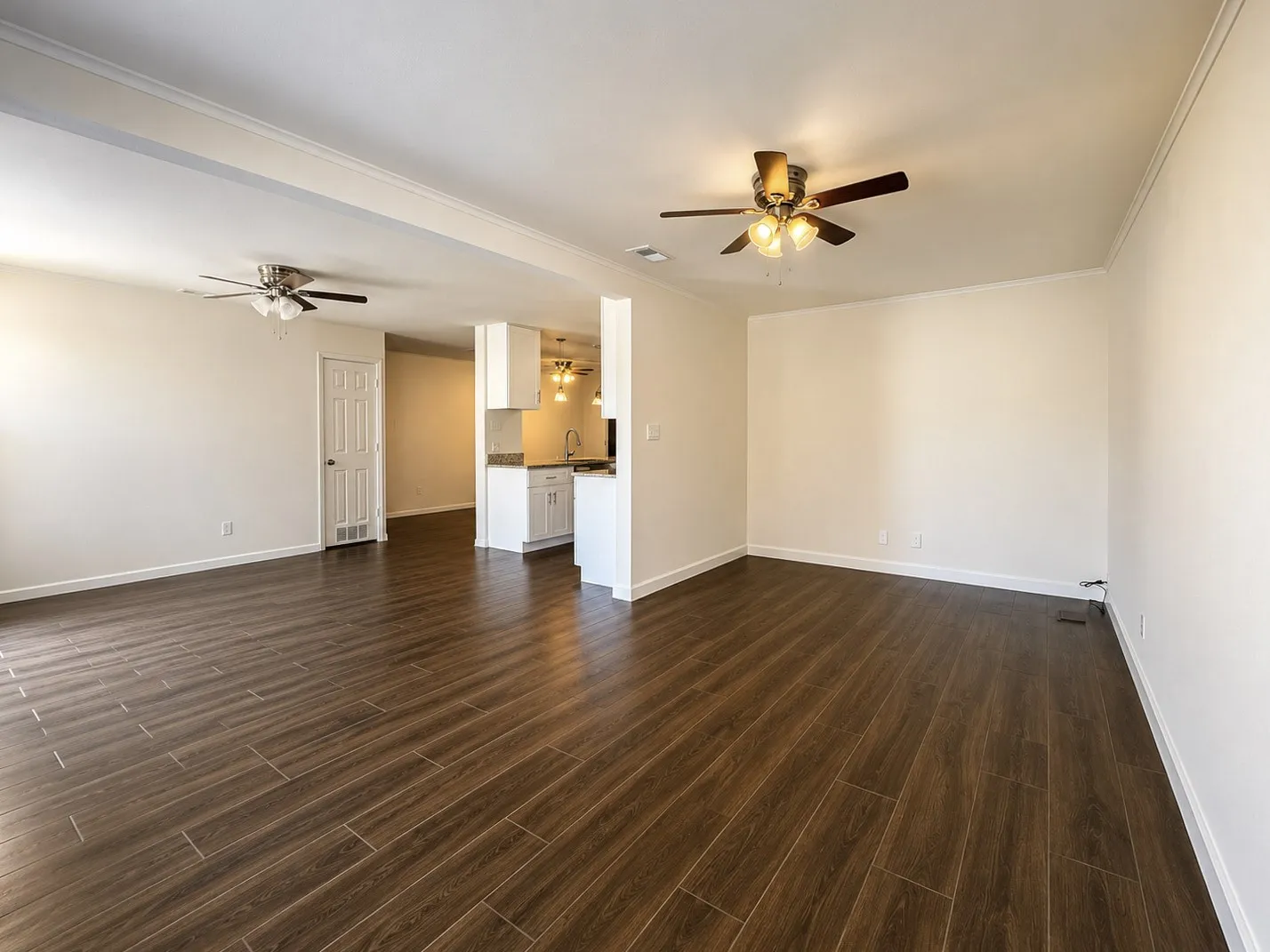 Spacious interior featuring wood-look tile flooring, white walls, and crown molding
