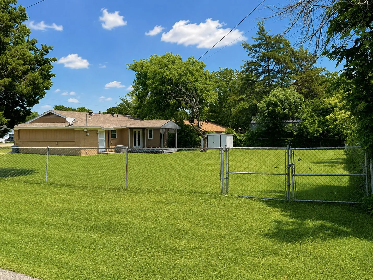 Expansive, fenced backyard featuring a manicured lawn and mature trees