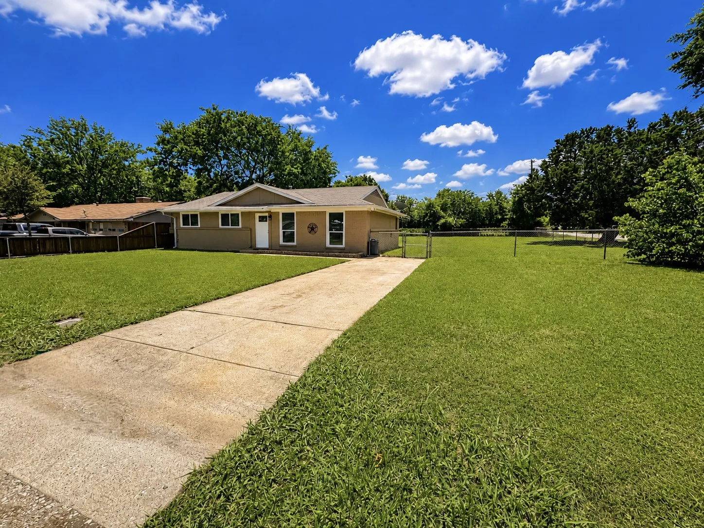 Expansive green lawn with a concrete driveway leading to a single-story residence