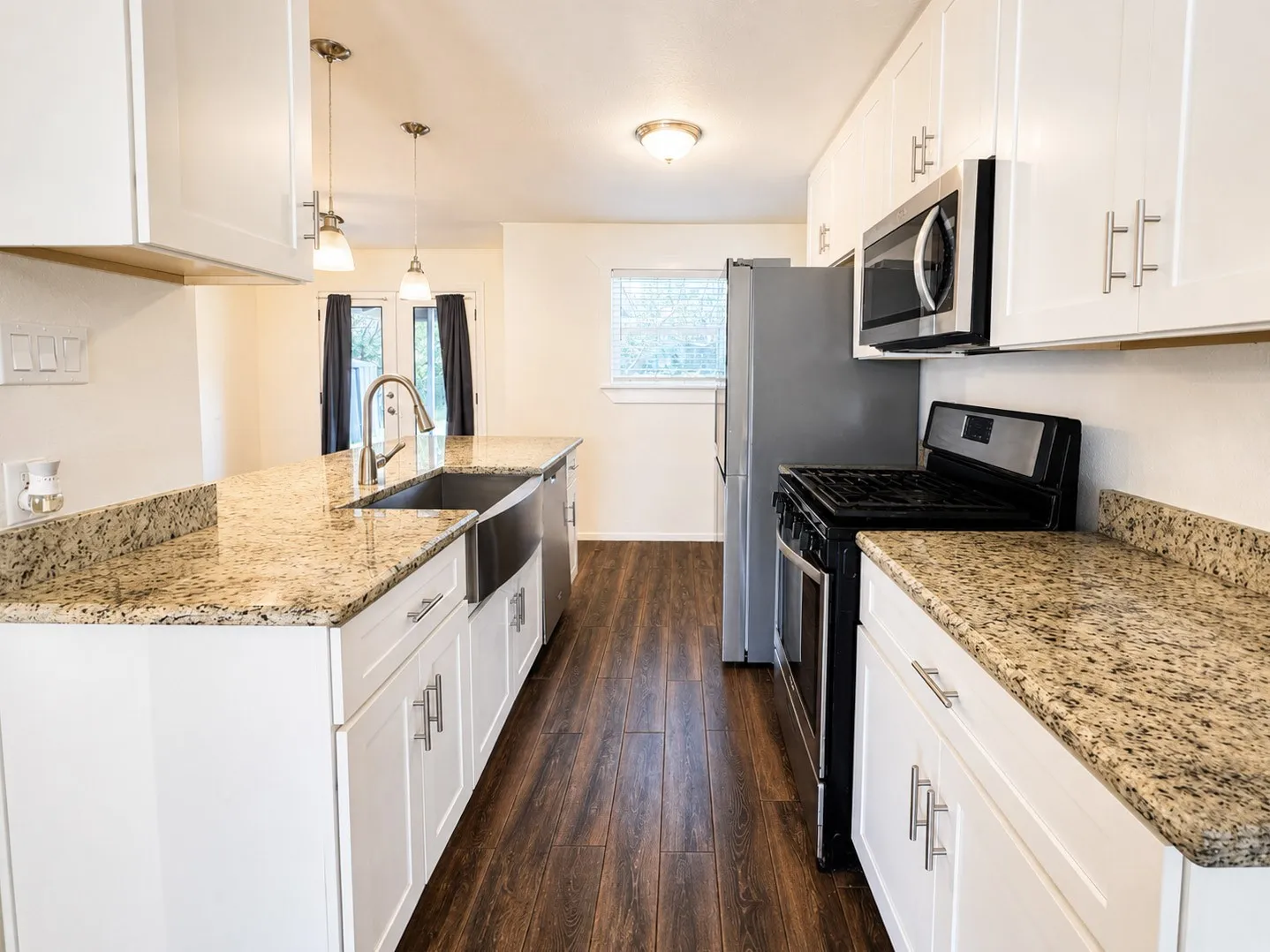 Kitchen featuring wood-finish flooring, white cabinetry with brushed nickel hardware, and granite countertops