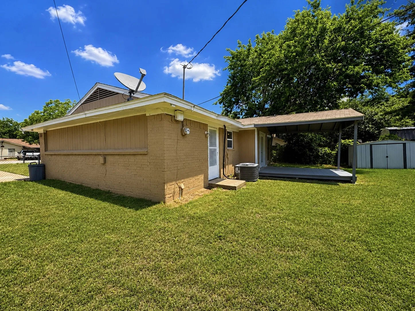 Expansive lawn with a covered patio structure and a storage shed