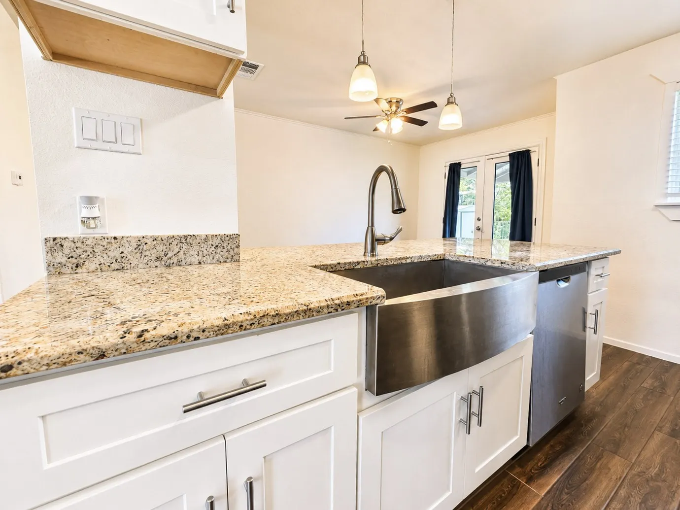 Kitchen island featuring a stainless steel farmhouse sink, gooseneck faucet, and granite countertops
