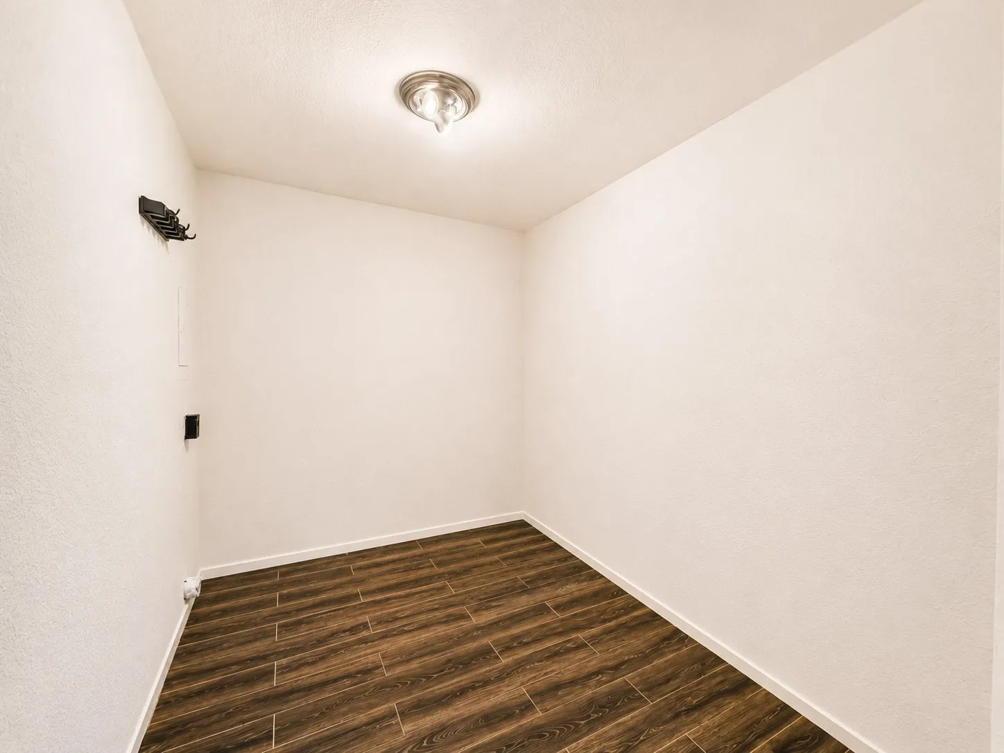 Compact room featuring wood-look tile flooring and neutral textured walls