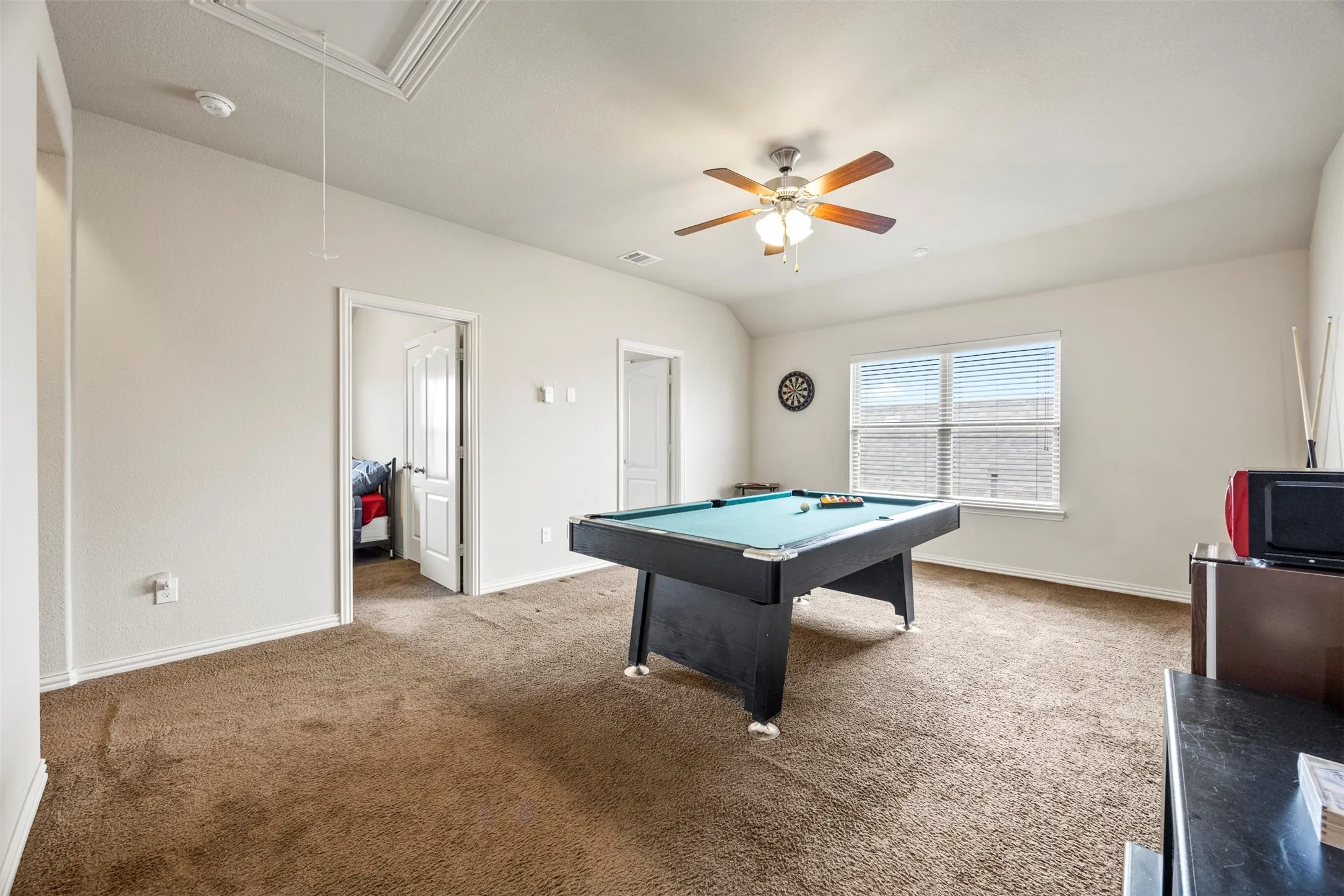 Spacious room with plush brown carpeting, light neutral wall tones, and a window with blinds