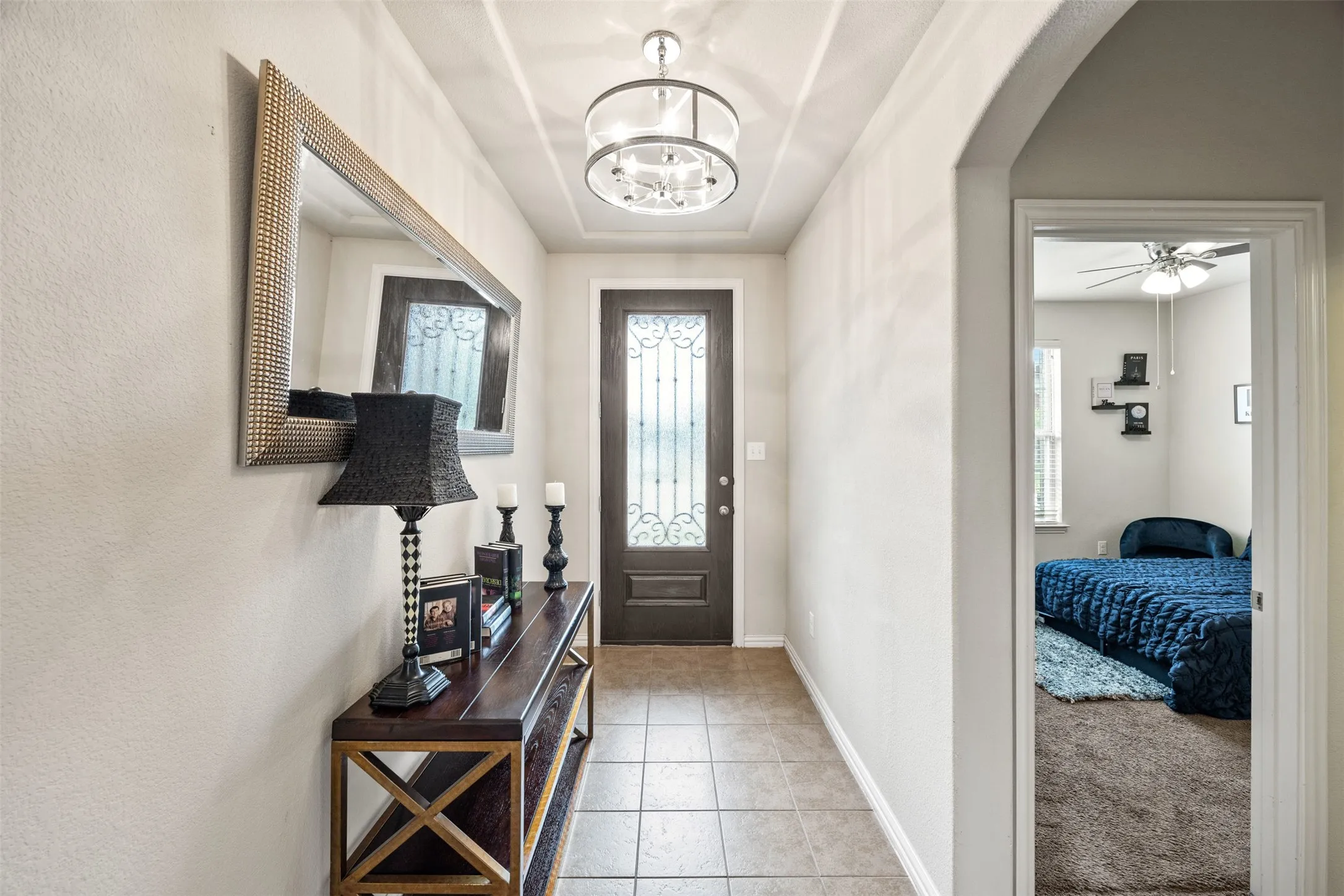 Foyer entry with tile flooring, decorative front door with transom window, tray ceiling, and a contemporary semi-flushmount light fixture