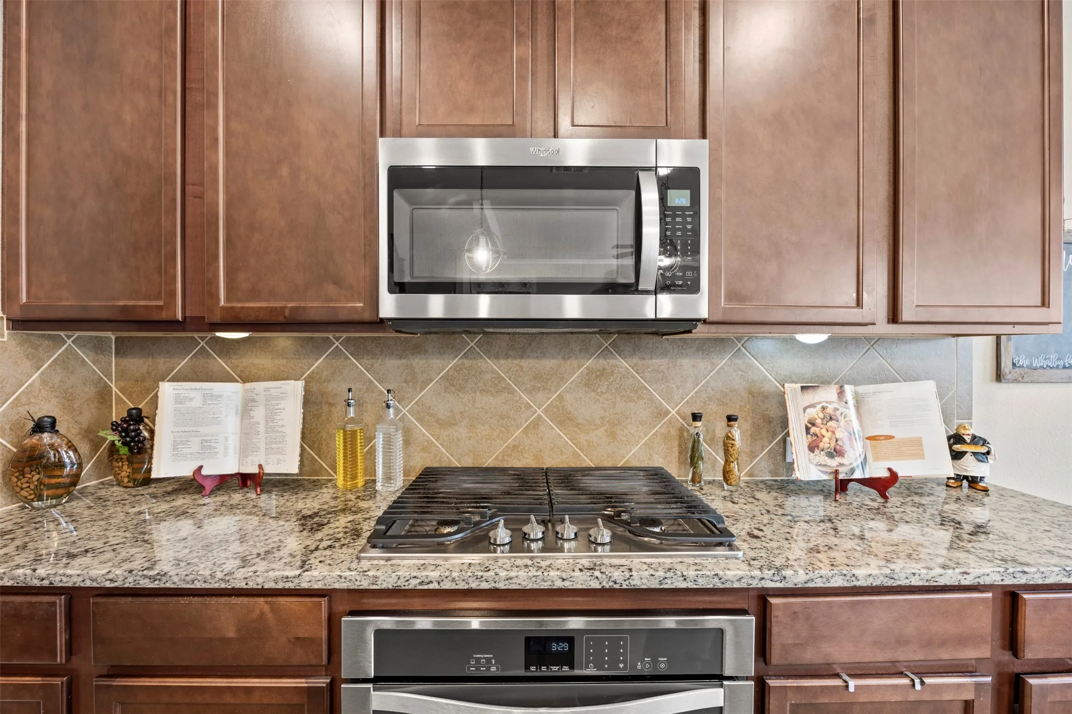 Kitchen featuring stone countertops, stainless steel appliances, wood cabinetry, built-in microwave, and tiled backsplash