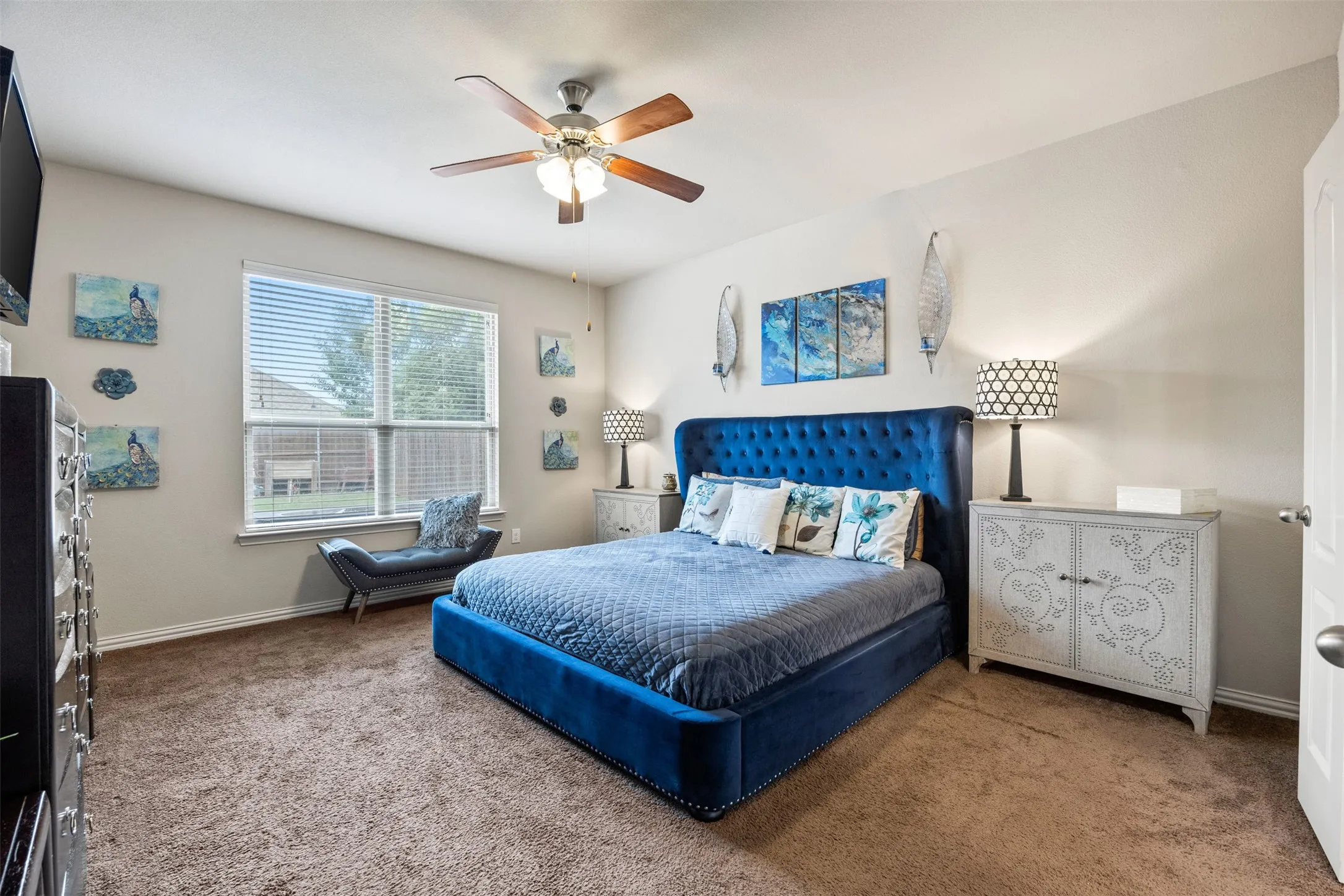 Spacious room with plush carpeting, a large window with blinds, and a ceiling fan with integrated lighting