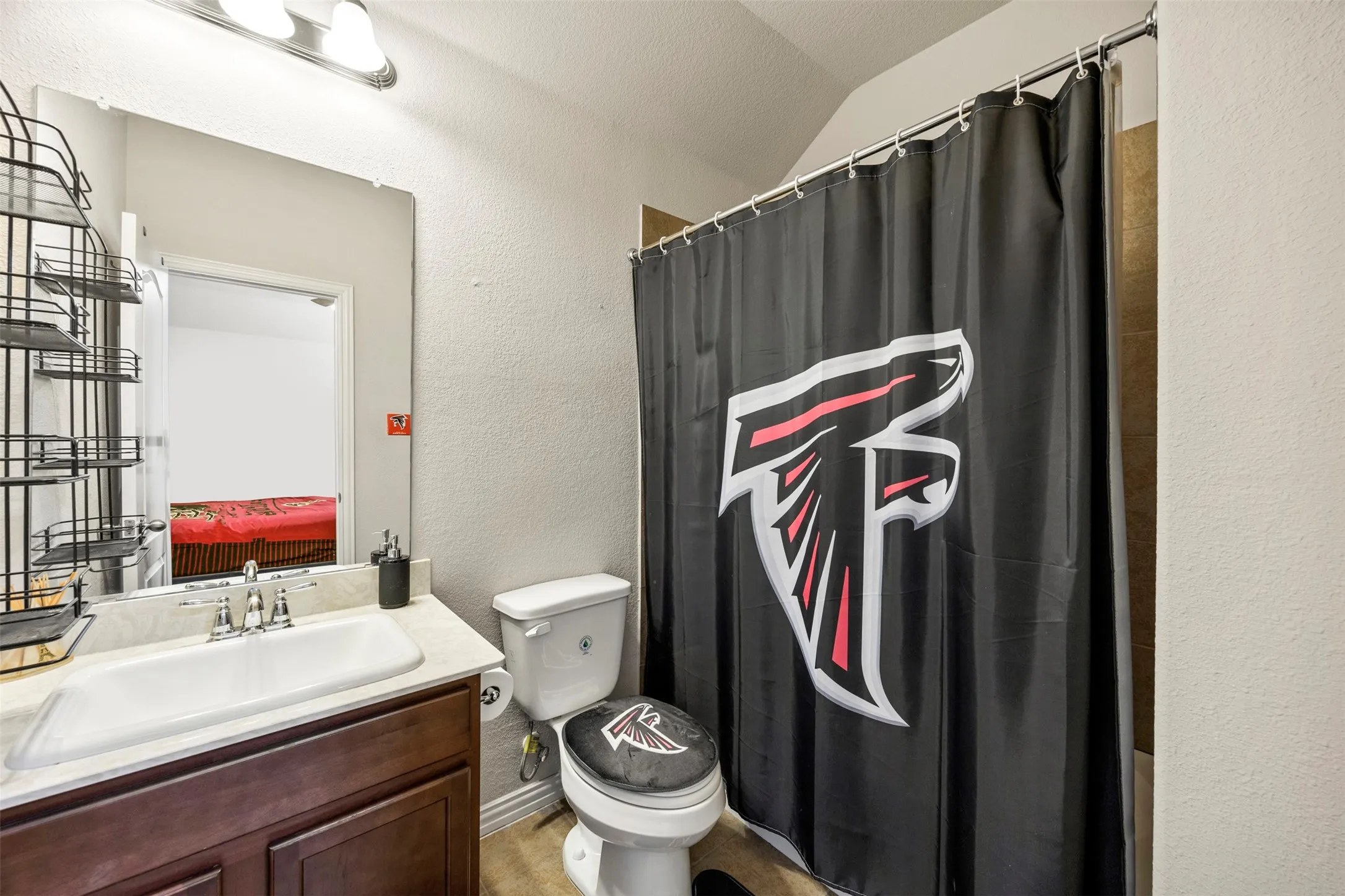 Bathroom featuring a dark wood-finish vanity with an integrated sink, polished chrome faucet, and overhead bar lighting