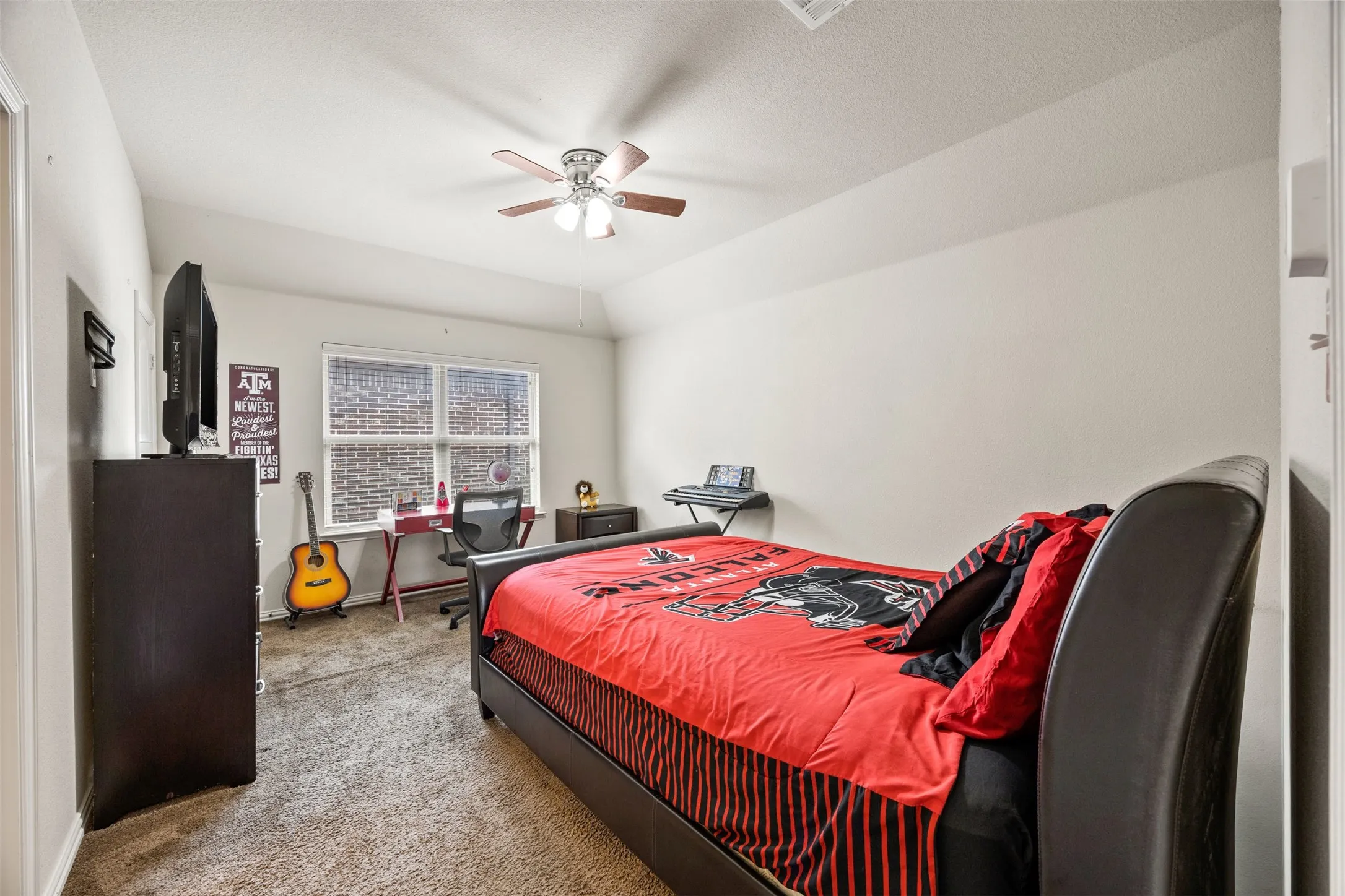 Carpeted room featuring a ceiling fan with light fixture, a window with brick exterior visibility, and a built-in closet