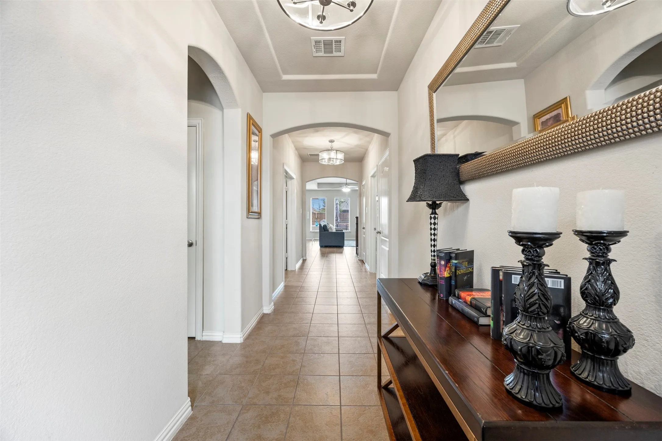 Long hallway featuring tile flooring, arched doorways, a coffered ceiling, and recessed lighting