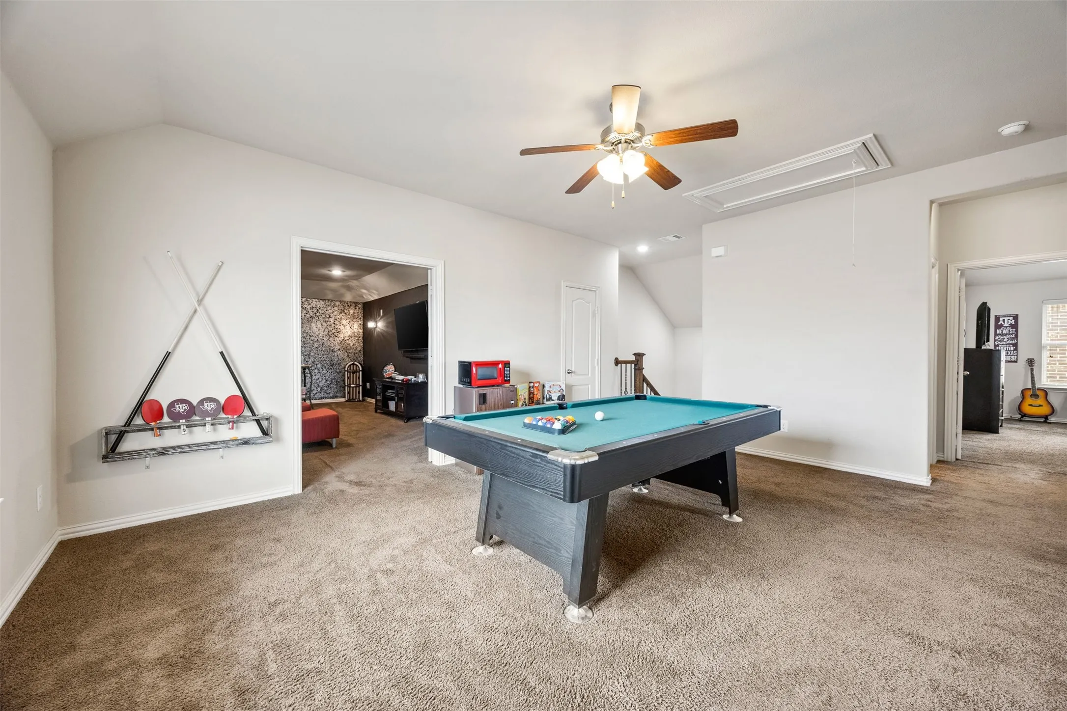 Spacious bonus room featuring vaulted ceilings, a ceiling fan with integrated lighting, and carpet flooring