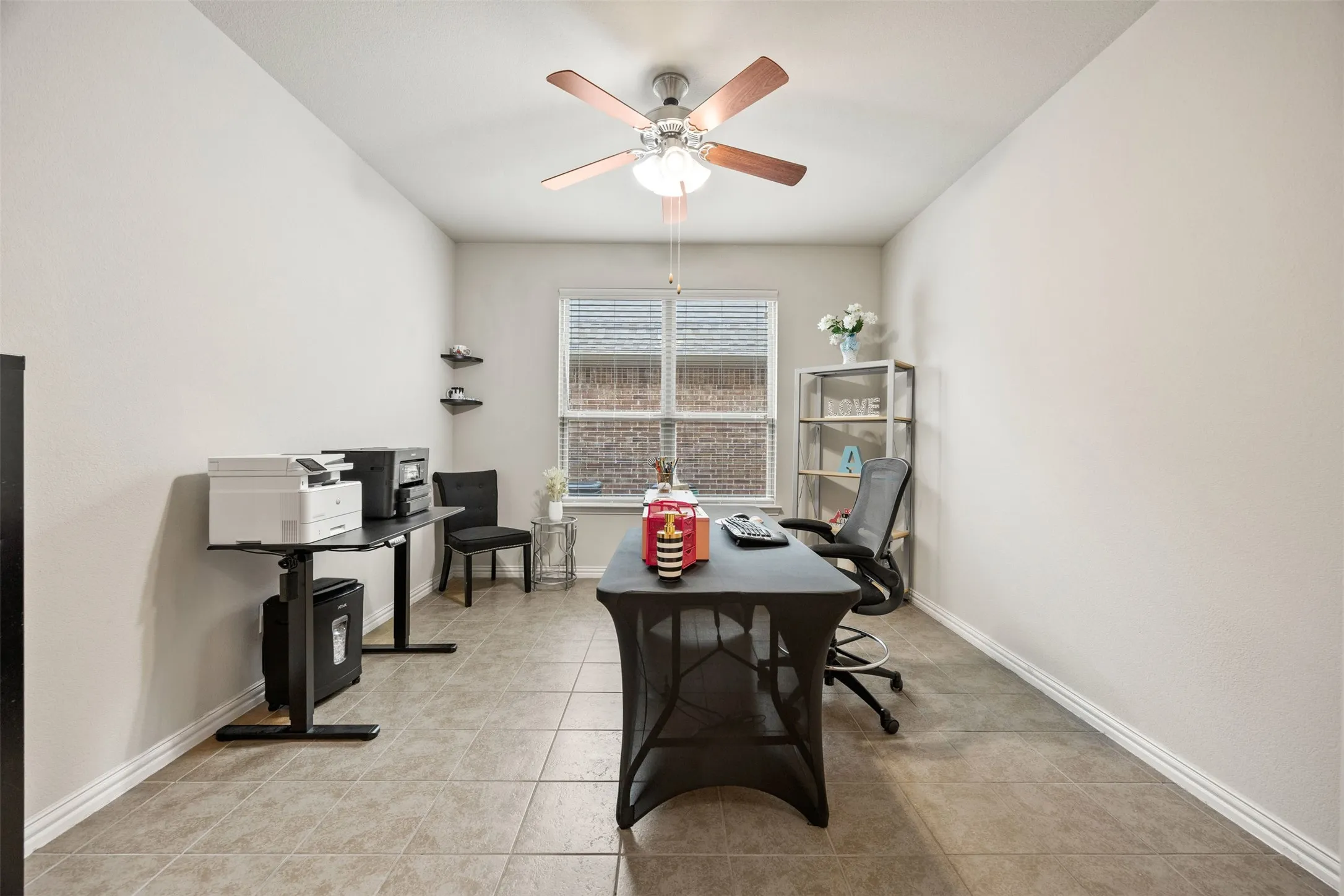 Spacious room featuring neutral paint, tiled flooring, a window with horizontal blinds, and a ceiling fan with light fixture