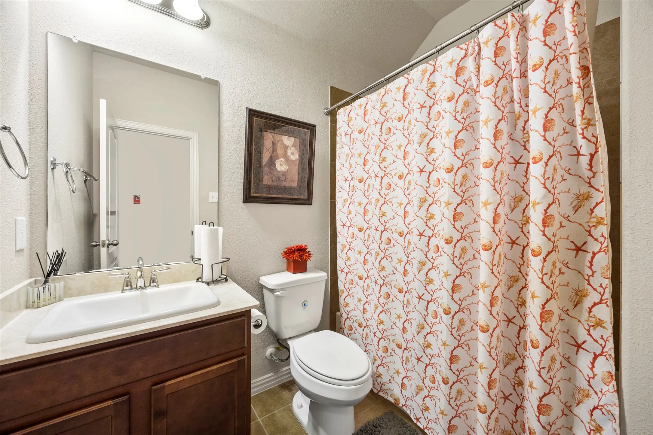 Bathroom featuring a single vanity with a white rectangular sink, a polished chrome faucet, a large frameless mirror, and a toilet