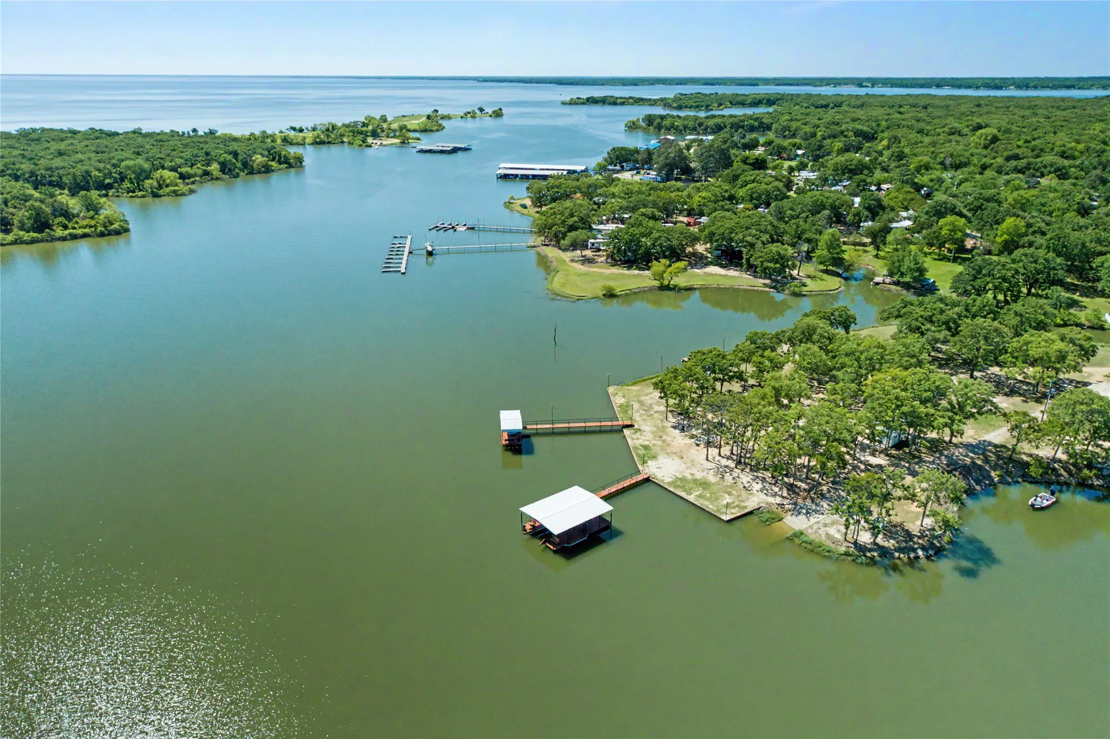 Waterfront property featuring multiple boat docks, mature trees, and direct water access