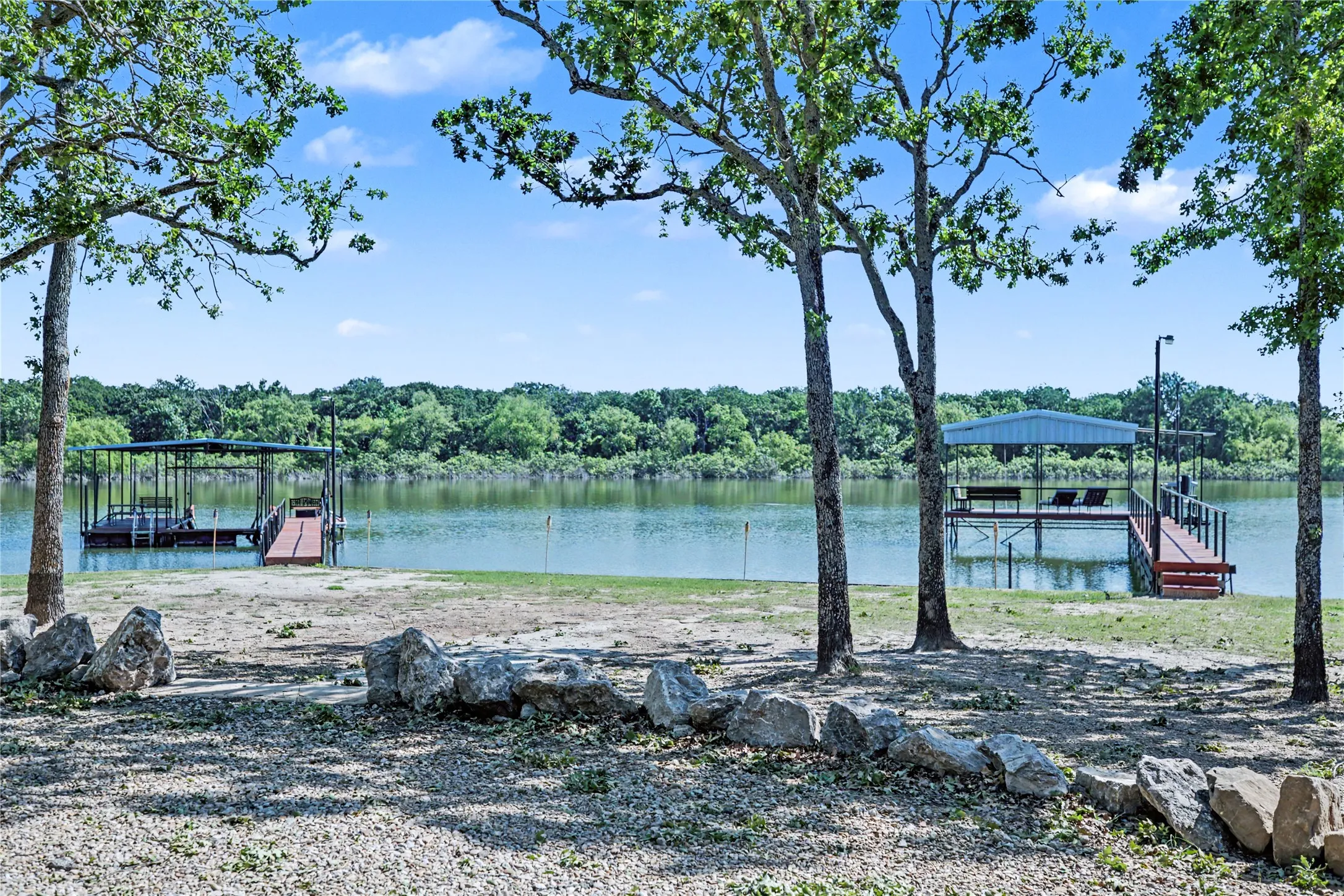 Waterfront property featuring two covered boat docks, each with a wooden walkway