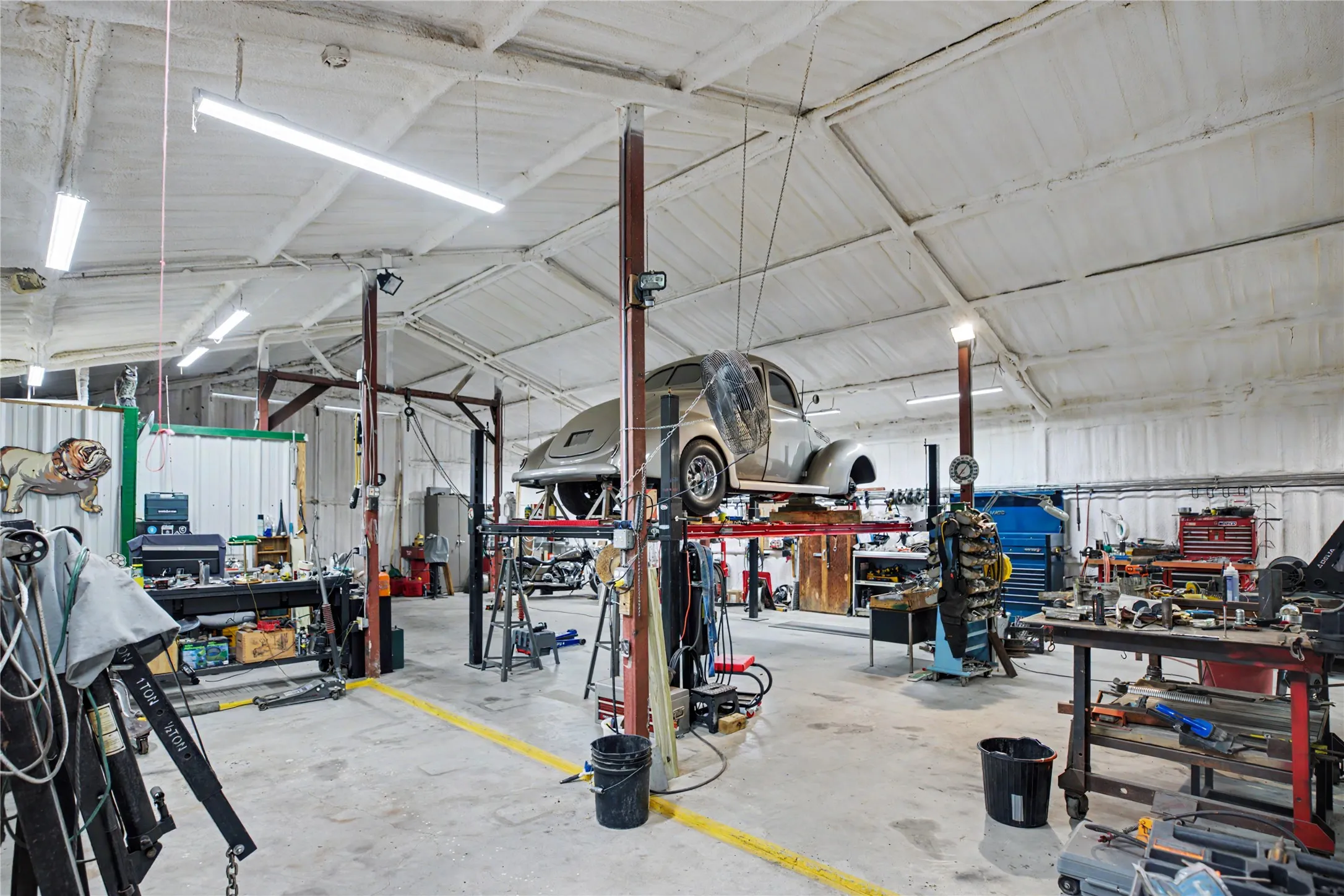 Spacious industrial interior featuring a high vaulted ceiling, exposed structural beams, and concrete flooring