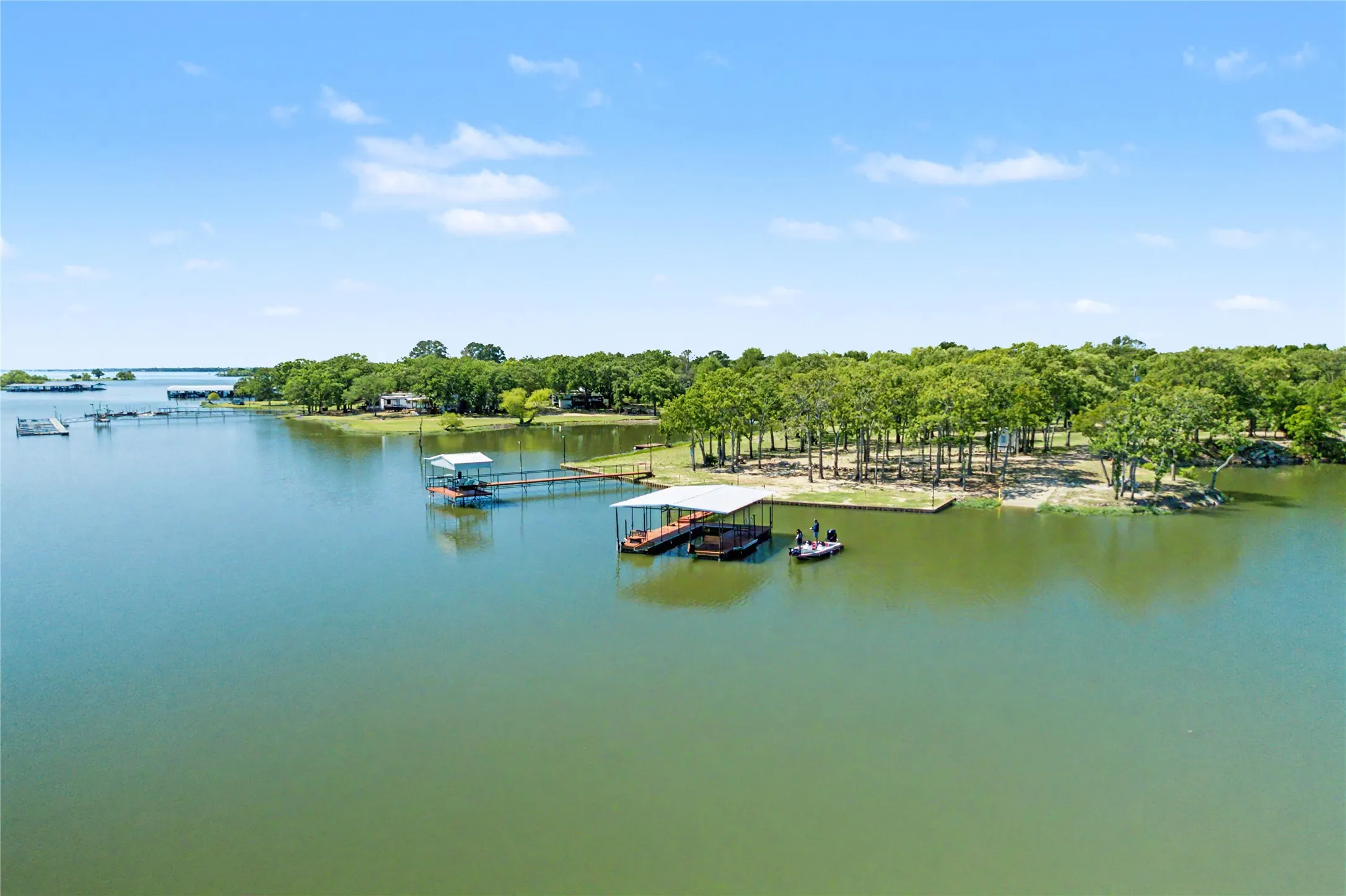 Waterfront property featuring multiple boat docks, a covered boat slip, and a forested shoreline