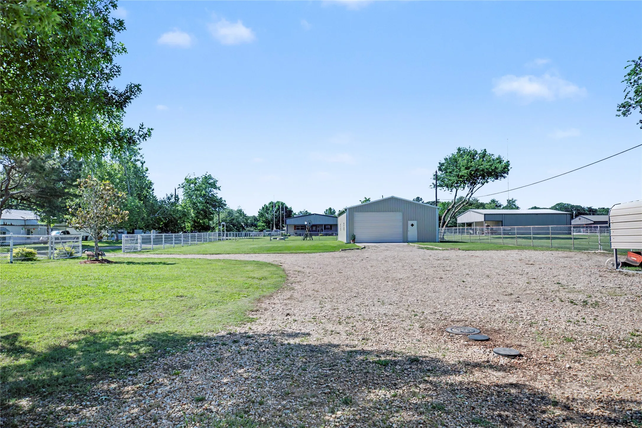 Expansive gravel driveway leading to a metal building featuring a roll-up garage door and an entry door