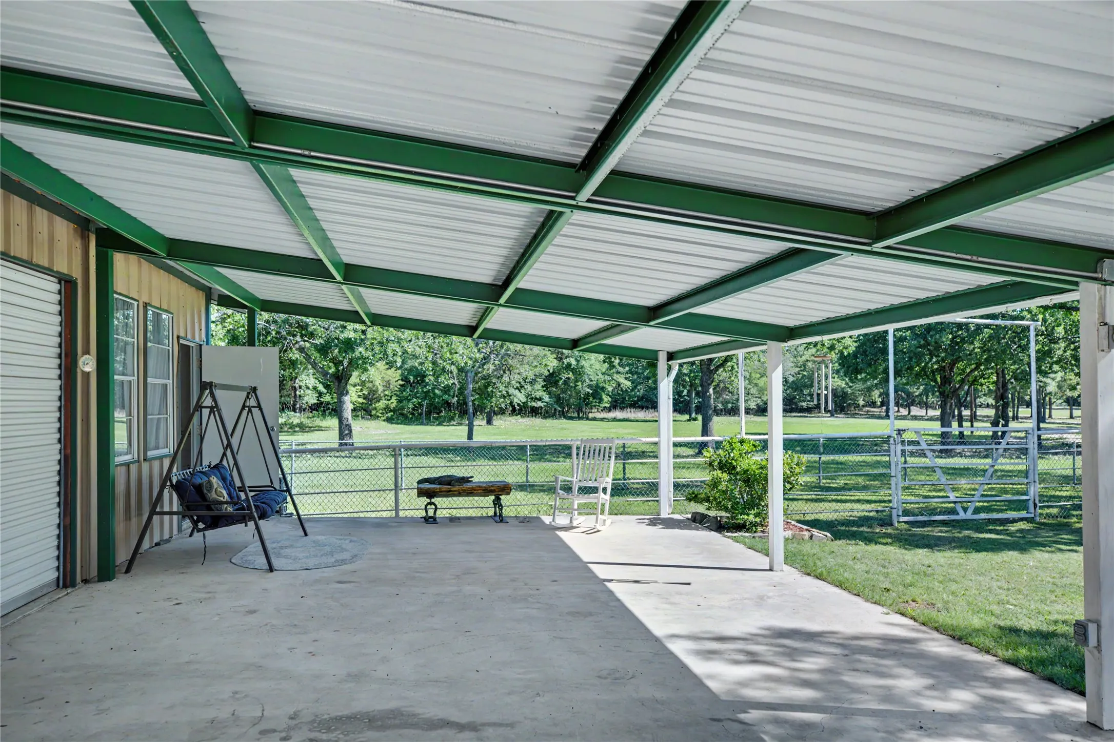 Expansive covered patio featuring a concrete surface and a green metal roof structure