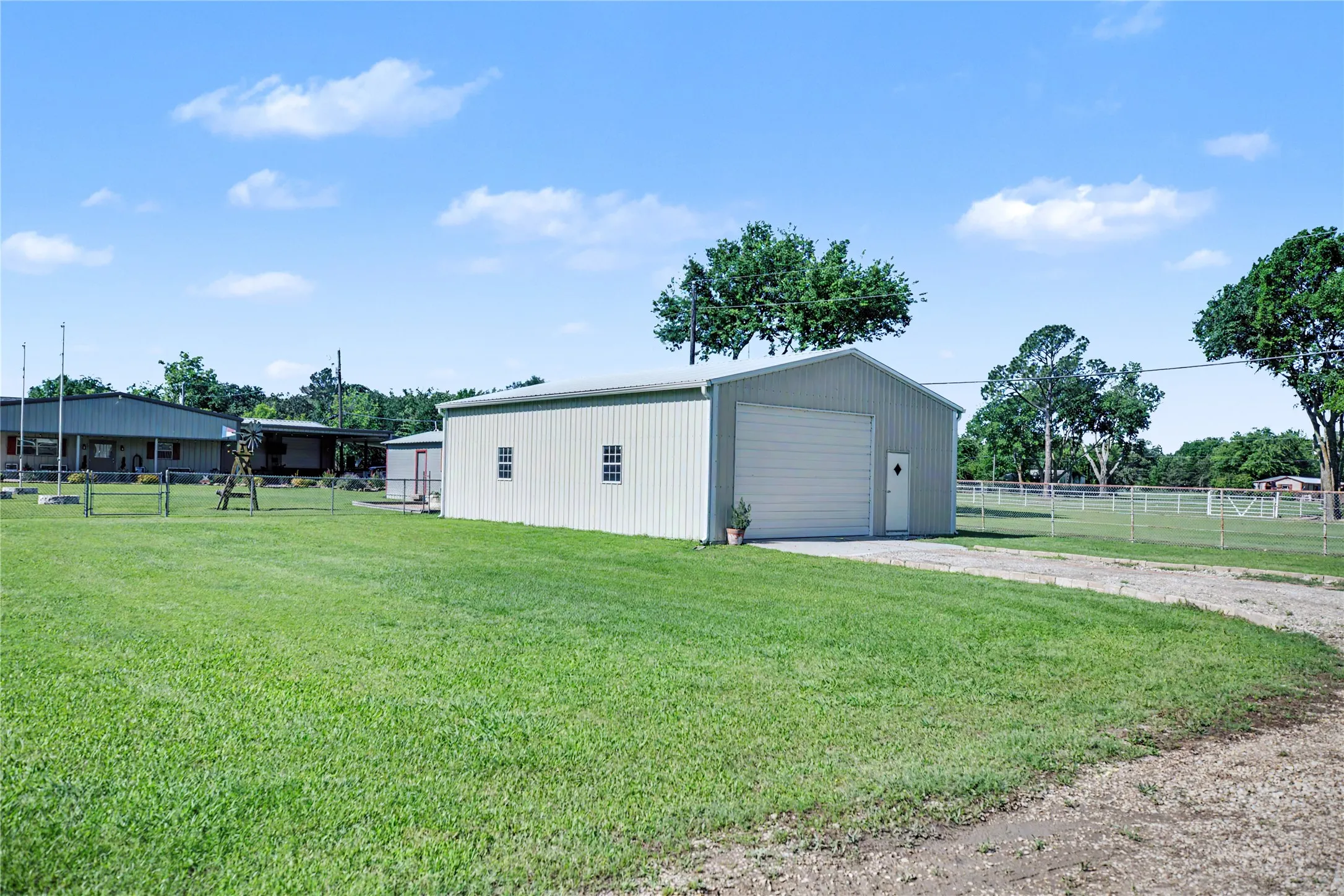 Metal-sided outbuilding featuring a roll-up garage door, pedestrian entry, and multiple windows
