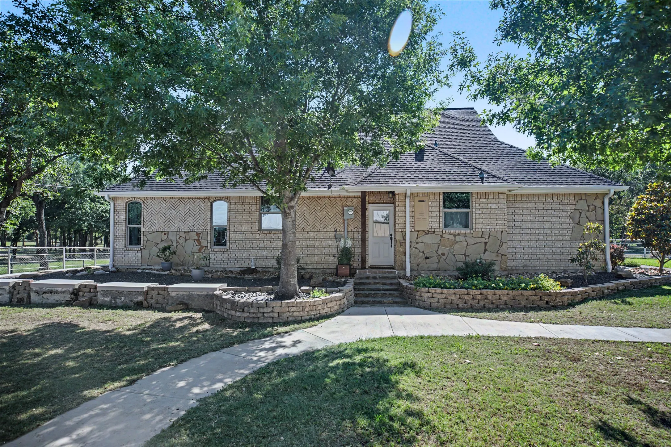Brick and stone exterior featuring multiple mature trees