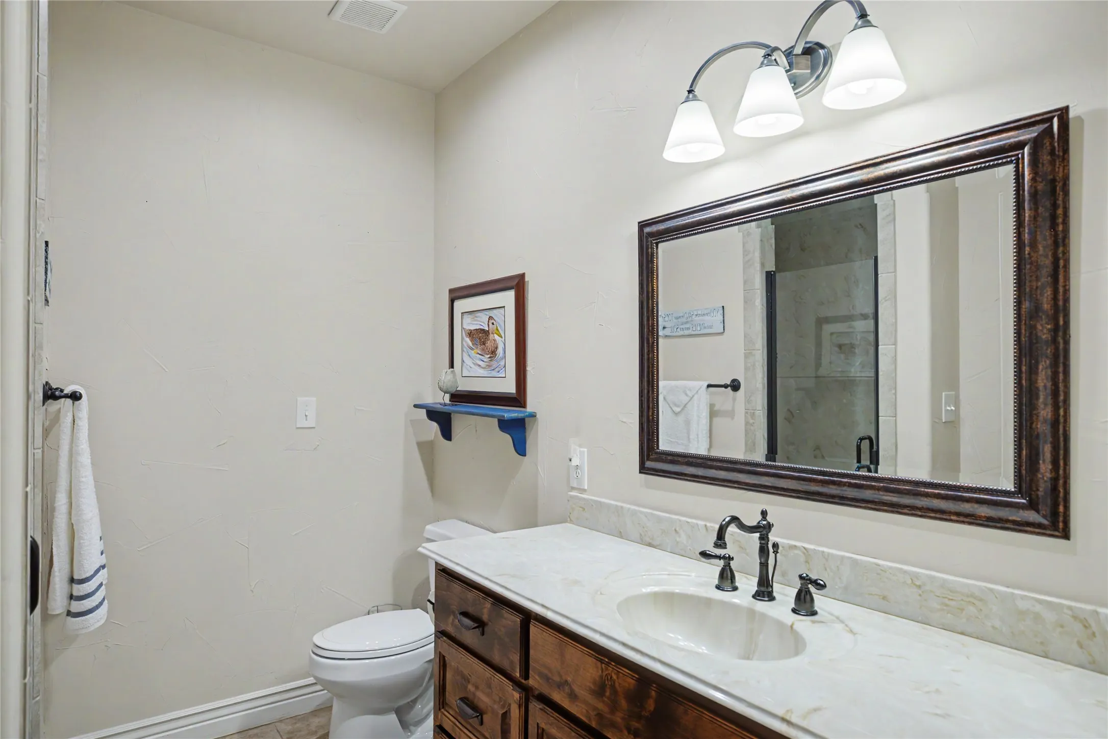 Bathroom vanity with a light-toned countertop, integrated oval sink, and dark bronze-finish fixtures