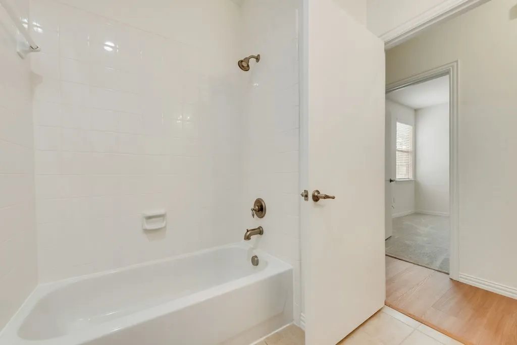 White tiled shower and bathtub combination with bronze fixtures