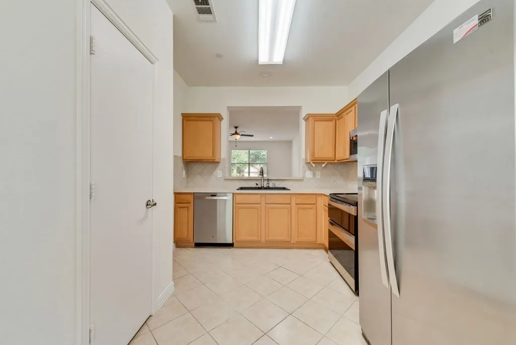 Kitchen featuring wood cabinetry, stainless steel appliances, and a tiled backsplash